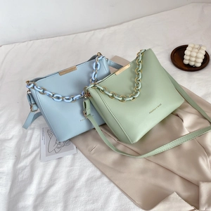 Minimalist bucket bags in light blue and green with acrylic chain handles and long straps