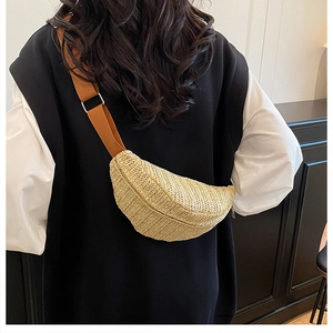 Detailed view of woven straw crossbody bag with adjustable wide fabric strap and moon shape