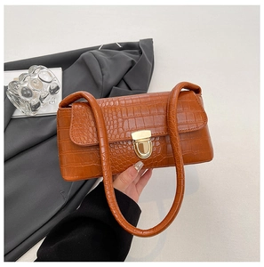 Detail of brown crocodile pattern shoulder bag with a stylish golden U-shaped buckle