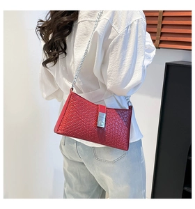 Détail d'un sac bandoulière rouge tressé avec chaîne argentée sur chemise blanche