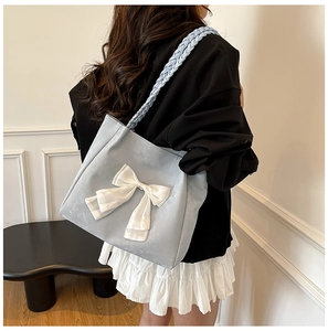Detail of light blue tote bag featuring white silk bow and woven shoulder strap