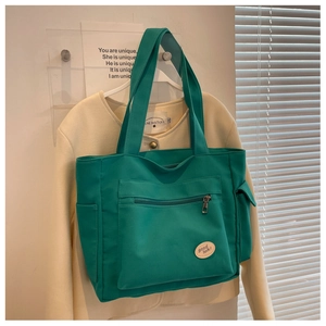 Detail of green canvas tote bag showing side pocket and high-quality textured fabric