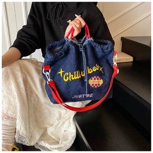 Detail of blue denim tote bag with red handles and Chillybest embroidery on raw edge fabric