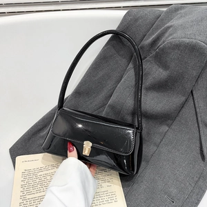 Glossy black patent leather baguette bag with a gold buckle on a stylish grey blazer