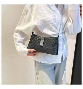 Détail du sac à bandoulière noir à motif crocodile avec une chaîne en métal argenté