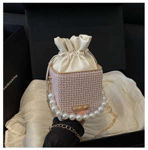 Detail of trendy bucket bag featuring large pearl handle and golden chain strap
