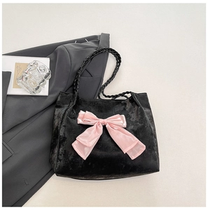 Detail of black velvet tote bag featuring a large pink bow and woven rope handles