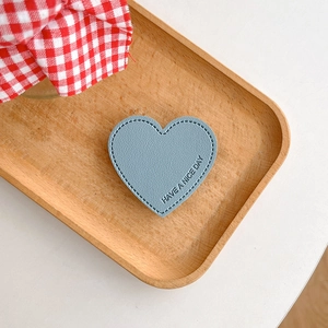 Detail of light blue heart leather phone grip with lychee texture and stitched edges