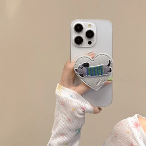 Detail of heart-shaped leather phone grip with embroidered dachshund puppy and stitching