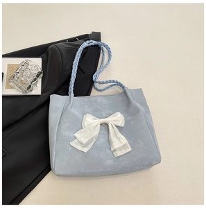 Detail of light blue tote bag with white bow and braided shoulder strap textures