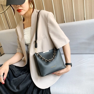Chic black bucket bag with gold chain strap shown on a model in a modern office setting