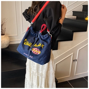 Detail of dark blue denim tote bag with Chill embroidery and red wide shoulder strap