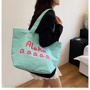 Detail of mint green canvas tote bag with pink Aloha text showing large capacity and size