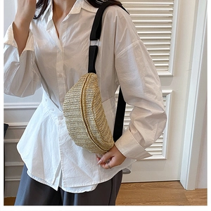 Detail of straw woven chest bag with adjustable black canvas strap and metal buckle