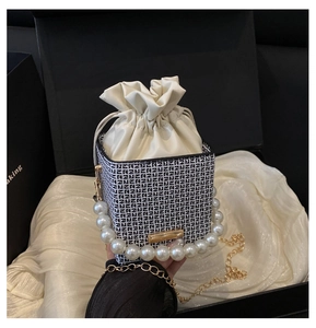Detailed view of luxury box bag with pearl handle, letter pattern, and gift packaging