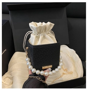Detail of mini bucket bag with pearl handle and woven texture on luxury silk background