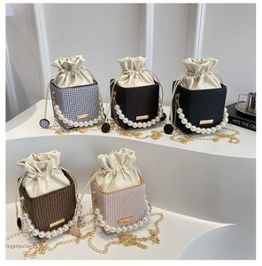 Close-up of stylish cube bucket bags with pearl handles and gold chain straps