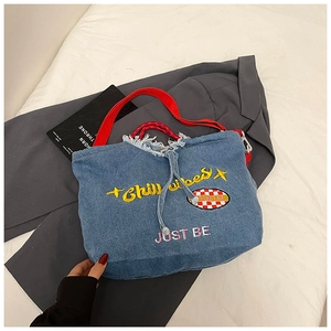 Detail of embroidered Chill Vibes letters and red woven strap on denim tote bag