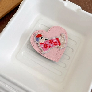 Detail of heart-shaped pink leather phone socket with cute dog embroidery and stitching