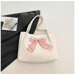 Detail of cream tote bag with large pink satin bow and woven rope handles
