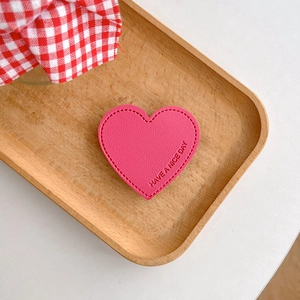 Detail of pink heart-shaped leather phone grip with Have a Nice Day embossing