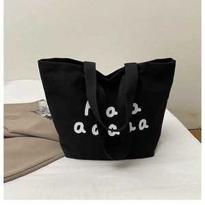 Close-up of a black canvas tote bag with white artistic lettering for daily commute