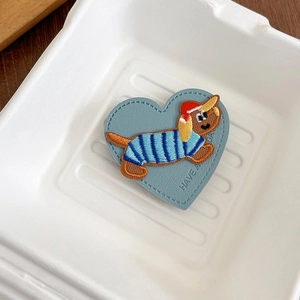 Detail of heart-shaped blue leather phone socket with dachshund dog embroidery
