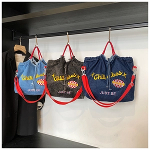 Detailed embroidery on denim tote bags with adjustable red straps and drawstring closure