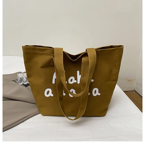 Detail of mustard yellow canvas tote bag with white lettering and sturdy shoulder straps