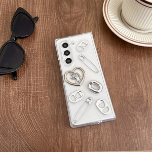 Detail of transparent phone case with punk Y2K silver heart charm and paperclip decor