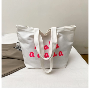 Detail of white canvas tote bag featuring thick fabric texture and pink bubble letter print