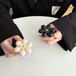 Vue détaillée des supports de téléphone en forme de fleur noir et blanc avec cœurs dorés