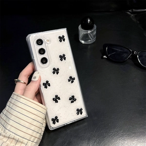 Detail of transparent phone case with nine 3D black bows on a glittery finish