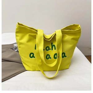 Close-up of bright yellow canvas tote bag with green artistic Hah a a a a letter print