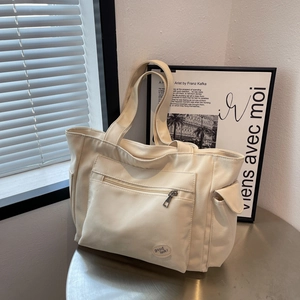 Large beige canvas tote bag with multiple pockets and shoulder straps for daily commuting
