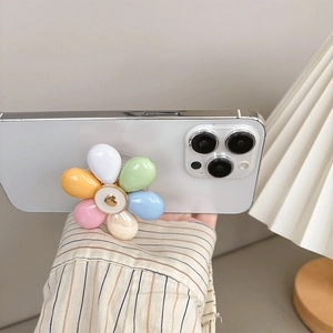 Détail du support de téléphone fleur macaron avec cœur doré sur un smartphone blanc