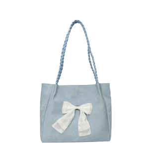 Light blue tote bag with large white bow and woven handle on white background
