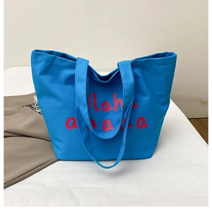 Detail of bright blue canvas tote bag featuring pink ahaha print and spacious opening