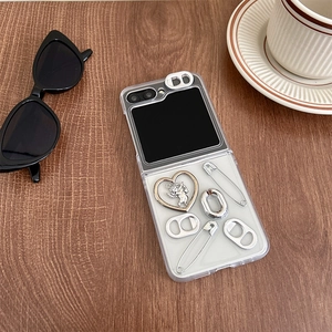 Detail of transparent folding phone case with metal heart and safety pins on wood