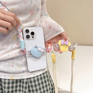Detailed view of a heart and bow phone back clip with a colorful braided lanyard strap.