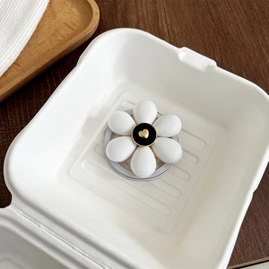 Détail du support téléphone en fleur avec pétales blancs et cœur doré au centre noir