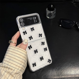 Detailed view of Samsung Z Flip case featuring 3D black bows on a white glitter background