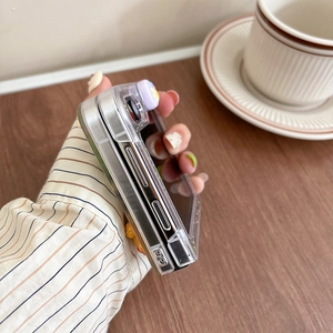 Detail of transparent phone case with purple floral charm on a foldable device