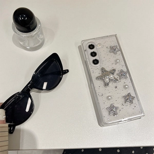 Detail view of transparent glitter phone case with silver stars and white pearls