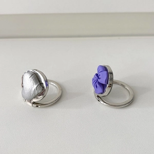 Detail of silver phone rings featuring a textured heart and 3D purple flower design