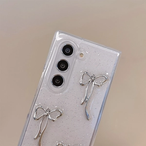 Macro detail of glitter texture and 3D silver bow accents on a white protective phone case