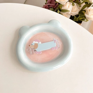 Close-up of a blue bear ceramic tray with a cartoon dachshund dog hair clip accessory