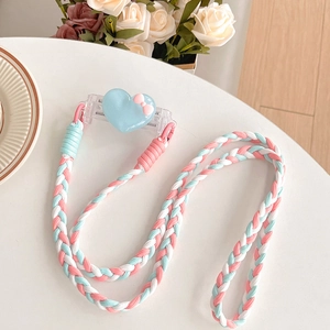 Detail view of heart-shaped phone clip with pink and blue braided crossbody strap