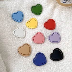 Multi-color heart-shaped adhesive phone ring stand collection on white texture.