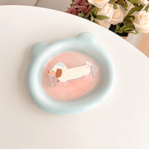 Detail of cute dachshund dog hair clip with a blue bear decorative tray on a white desk